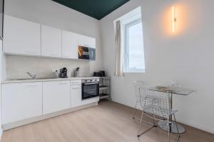 a kitchen with white cabinets and a table and chairs at Studio équipé avec parking gratuit in Villeneuve d'Ascq