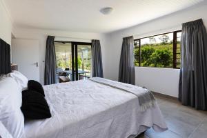 a bedroom with a white bed and a large window at Fungamukaba Sanctuary in Mossel Bay