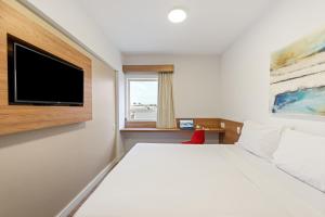 a bedroom with a large bed with a flat screen tv at Blue Tree Towers Jaguariúna in Jaguariúna