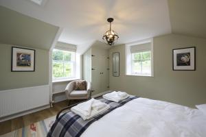 a bedroom with a bed and a chair and windows at Garden Cottage in Inverness