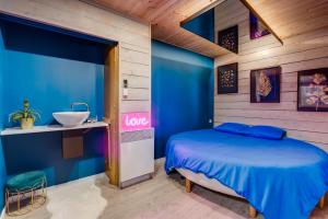 a blue bedroom with a bed and a sink at RelaxRoom Sauna Balnéothérapie Détente Bien-être in Lacasse