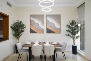ドバイにある13 - Stylish Palm view Family Apartment in Dorra Bay - Beach Accessの木製のテーブルと白い椅子のあるダイニングルーム