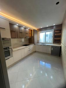 a kitchen with wooden cabinets and a white tile floor at Appartement Haut Standing 3 chambres proche gare et centre ville in Kenitra