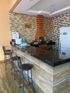 a kitchen with a counter with chairs and a refrigerator at Casa Maria Alice in Manhã