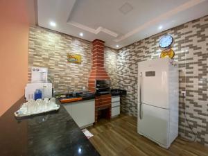 a kitchen with a white refrigerator and a clock on the wall at Casa Maria Alice in Manhã