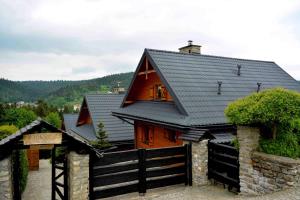 una casa de madera con techo negro y valla en Alpejskie Domy Ski House, en Krynica-Zdrój