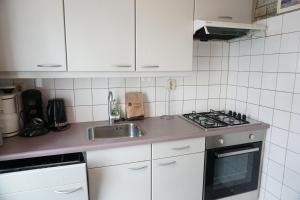 una cucina bianca con lavello e fornello di Kustverhuur, Park Schoneveld, Strandparel 365 a Breskens