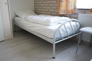 un letto con lenzuola bianche e cuscini sopra di Kustverhuur, Park Schoneveld, Strandparel 365 a Breskens