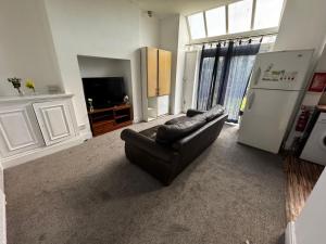 a living room with a black leather couch and a refrigerator at Double-Bedroom in the Heart of Salford Manchester GCSW1 Perfect for Short Stays in Manchester