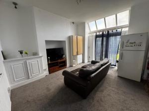 a living room with a leather couch and a refrigerator at Double-Bedroom in the Heart of Salford Manchester GCSW1 Perfect for Short Stays in Manchester