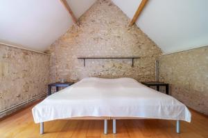 a bed in a room with a stone wall at Maison de campagne sud Touraine avec piscine 8px in Crouzilles +42 photos