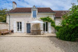 an external view of a house with a table and an umbrella at Maison de campagne sud Touraine avec piscine 8px in Crouzilles