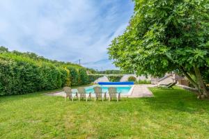 a group of chairs sitting in the grass next to a pool at Maison de campagne sud Touraine avec piscine 8px in Crouzilles