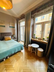 a bedroom with a bed and a table and two windows at Apartamenty Narutowicza 52 parking free in Lublin
