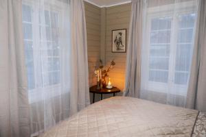 a bedroom with white curtains and a bed and a window at Huset Vårt - Bed and Breakfast in Hornindal