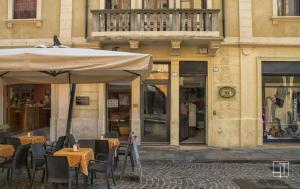 un ristorante con tavoli e ombrellone di fronte a un edificio di HT - Elegante mini in Prato della Valle a Padova