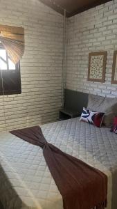 a large bed in a bedroom with a brick wall at Chalés de Imbassaí - Chalé 4 in Mata de Sao Joao +20 photos