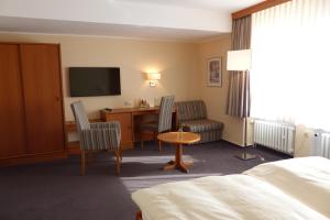 ein Hotelzimmer mit einem Bett, einem Schreibtisch und einem TV in der Unterkunft Hotel Hansa in Herford