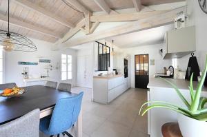 eine Küche und ein Esszimmer mit einem Tisch und blauen Stühlen in der Unterkunft Villa Coraly - piscine chauffée et jardin in Sainte-Marie-de-Ré