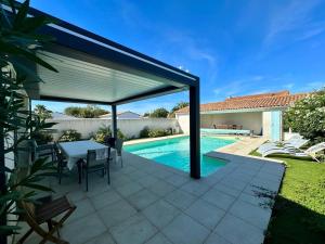 eine Terrasse mit Tisch und Pool in der Unterkunft Villa Coraly - piscine chauffée et jardin in Sainte-Marie-de-Ré + 13 Fotos