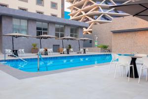 a swimming pool with tables and chairs and umbrellas at Palms by Eagles Airport City, Formerly Holiday Inn in Accra