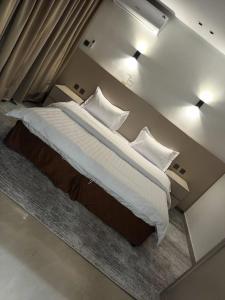 a bedroom with a large bed with white sheets and pillows at ركن فينيسيا للشقق المخدومة in Hail +11 photos