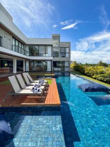 a large building with a swimming pool with lounge chairs at Nossa Casa | Frente Mar, 5 Suítes Exclusivas in Praia do Forte