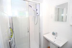 une salle de bain blanche avec une douche et un lavabo dans l'établissement Harbour Escape, à Porthmadog 17 autres photos