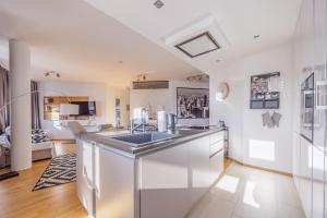 a kitchen with a sink and a living room at Luxury Apartment Villach City in Villach