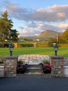 a stone pathway with flowers and a mountain in the background at Lissadell Lodge in Carney