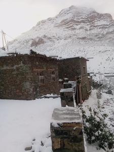 a stone building in the snow with a mountain in the background at Gite Itran Taghia in Taghia +3 photos