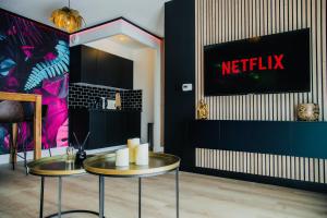a room with two tables and a netflix sign on a wall at Love Room - Balnéo - Nuit Insolite - Intimité in Toulouse +11 photos