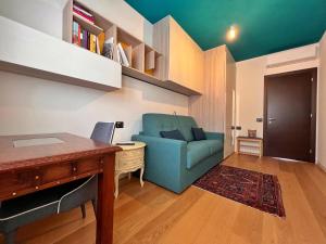 a living room with a blue chair and a desk at Casa Alce in Chiavenna