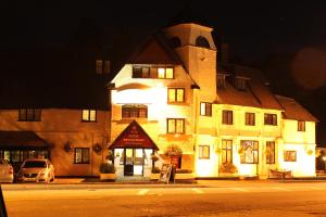 a lit up building on a street at night at The Devil's Punchbowl Hotel in Hindhead