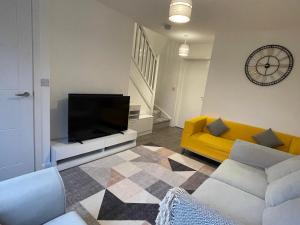 a living room with a tv and a yellow couch at Cozy double room in Wavendon