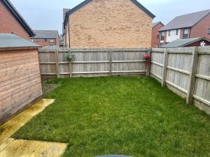 a backyard with a wooden fence and green grass at Cozy double room in Wavendon