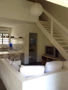 ein Wohnzimmer mit einer weißen Couch und einer Treppe in der Unterkunft Vila Giulia in Maresias