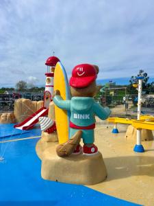 ein ausgestopfter Teddybär steht neben einem Surfbrett in einem Wasserpark in der Unterkunft Vlugtenburg in s-Gravenzande