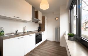 a kitchen with white cabinets and a sink at BEGE APARTMENTS ConnectPoint in Nettetal