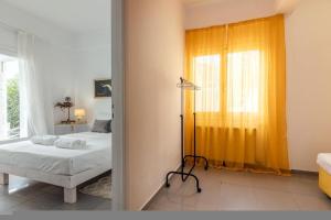a bedroom with a bed and a yellow curtain at White Cycladic House with Jacuzzi in Limín Khersonísou