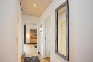 a mirror hanging on a wall in a hallway at Welcome in - Apartment 59-G 'Leni' direkt an der Piste, mit Balkon, Sauna und Schwimmbad in Winterberg +45 photos