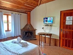 - une chambre avec un lit, une cheminée et une télévision dans l'établissement Pousada Chalés Vista da Serra, à Visconde de Mauá