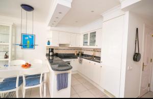 パタラバカにあるPrimera línea Montemarina Anfi del Marの白いキャビネットとテーブルと椅子のあるキッチン +5枚の写真