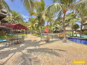 a resort with a pool and tables and chairs and palm trees at Parque das Ilhas in Mangabeira
