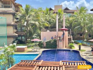 a pool at a resort with palm trees and a person standing on a platform at Parque das Ilhas in Mangabeira