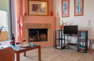 a living room with a fireplace and a table with wine glasses at Barbati Angela's Garden Sea View in Barbati