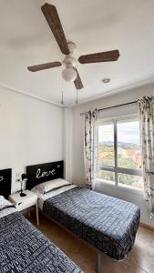 Un dormitorio con dos camas y un ventilador de techo. en Cala AZUL Gran Terraza con BBQ, en Cabo de Palos