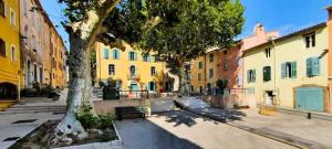 a tree in the middle of a street with buildings at La Maisonnette de vacances avec piscine privée pour 2 pers in Lorgues