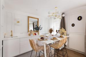 eine weiße Küche mit einem Tisch mit Stühlen und einem Spiegel in der Unterkunft Suite de Luxe à 10 min de Paris - Sauna, Cinéma in Bagneux
