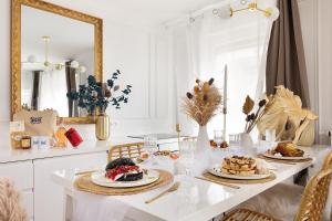 ein weißes Esszimmer mit einem Tisch mit Essen drauf in der Unterkunft Suite de Luxe à 10 min de Paris - Sauna, Cinéma in Bagneux